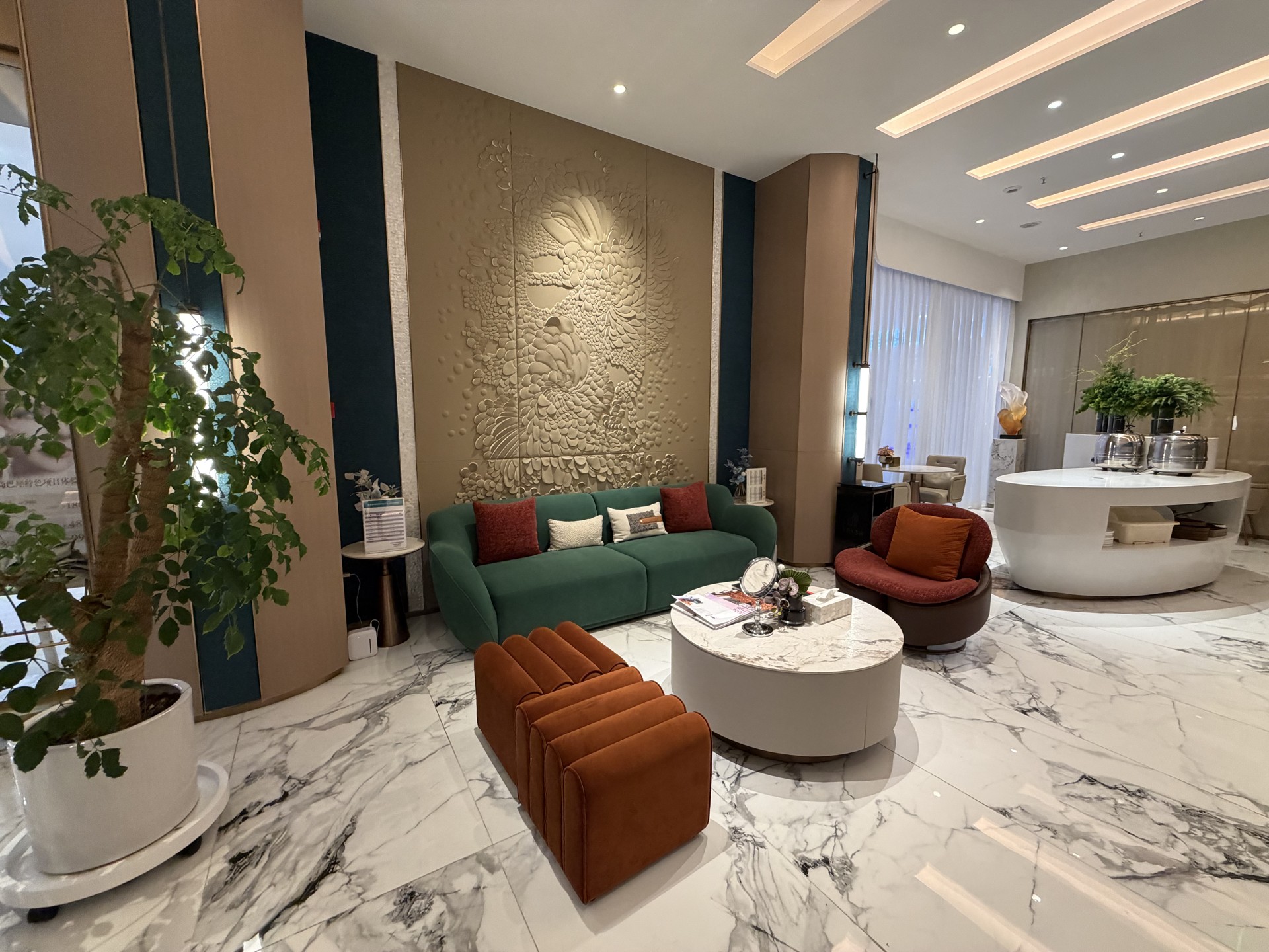 Finished reception lounge with emerald sofa, terracotta accent chairs and sculptural relief wall