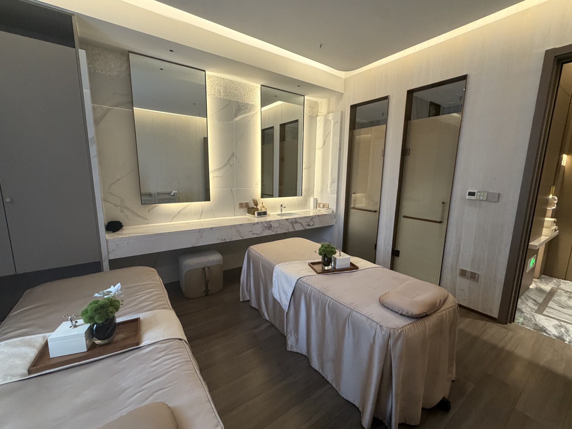 Completed twin-bed spa treatment room with neat linens, marble vanity and backlit mirrors