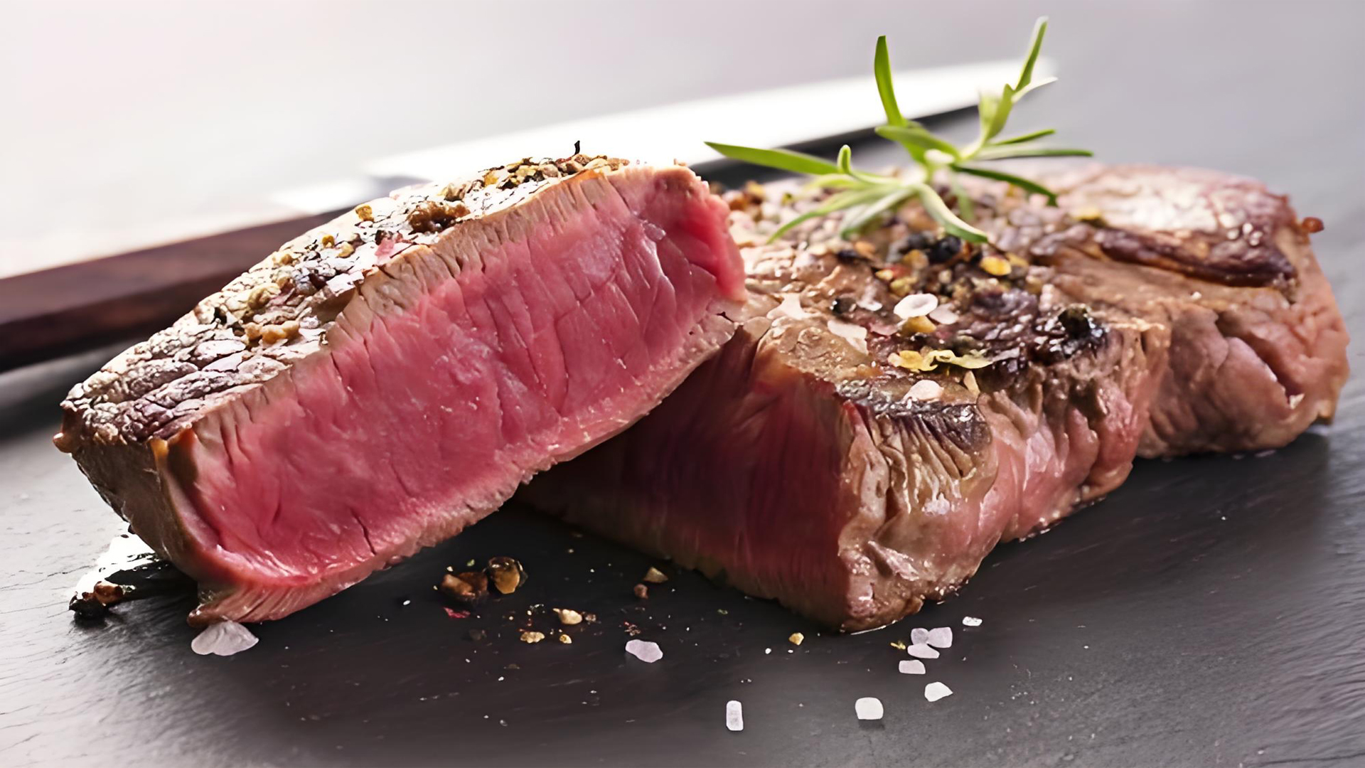 Sliced seared filet mignon with rosemary on slate, closeup